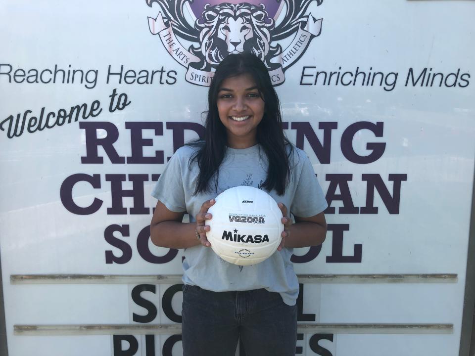 Redding Christian senior setter Sia Patel holds a volleyball in front of her school's sign on Monday, Aug. 22, 2022.