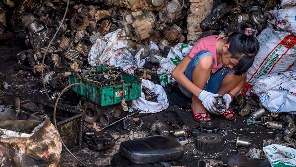 Adolescente reciclando componentes de baterías y otros desechos electrónicos en Vietnam