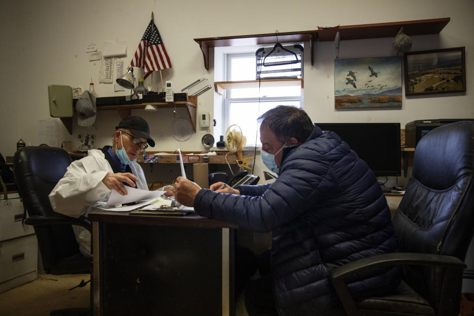 Rabbi Shmuel Plafker, left, and funeral director James Donofrio work in the office of Hebrew Free Burial Association's cemetery as they deal with a surge in burials, mostly of those who died from coronavirus, in the Staten Island borough of New York, Tuesday, April 7, 2020. Staffers find themselves exchanging texts about death certificates at 2 a.m. and fielding dozens of calls at a time. It takes its toll on everyone. (AP Photo/David Goldman)