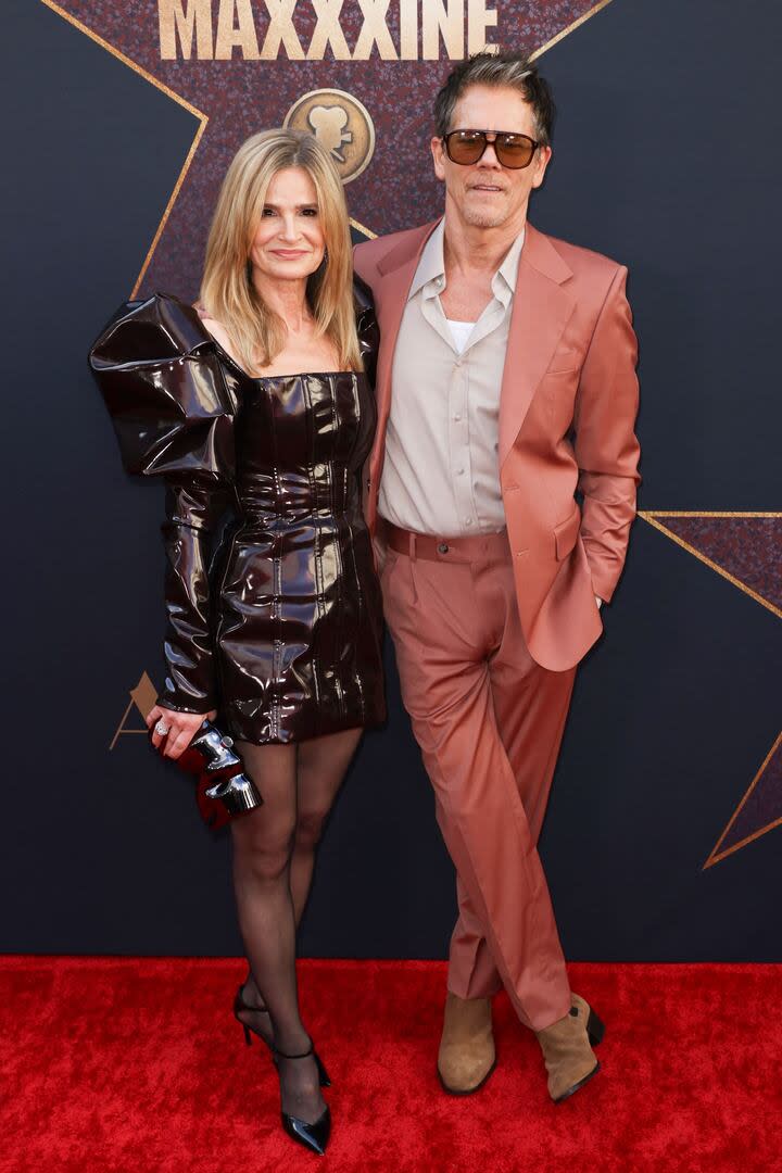 Kevin Bacon y su esposa, Kyra Sedgwick, derrocharon onda en el estreno mundial de MaXXXine en el Teatro Chino de Hollywood. Para recorrer la alfombra roja, el actor de Río Místico optó por un traje rosa viejo, una camisa beige, una camiseta de algodón blanca y unos lentes de sol vintage. Por su parte, la actriz de Fenómeno lució un vestido corto negro charolado con unas mangas voluminosas y tacos a tono
