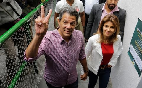 Workers' Party presidential candidate Fernando Haddad, accompanied by his wife Ana Estela, arrives at a polling station to cast his vote - Credit: AP