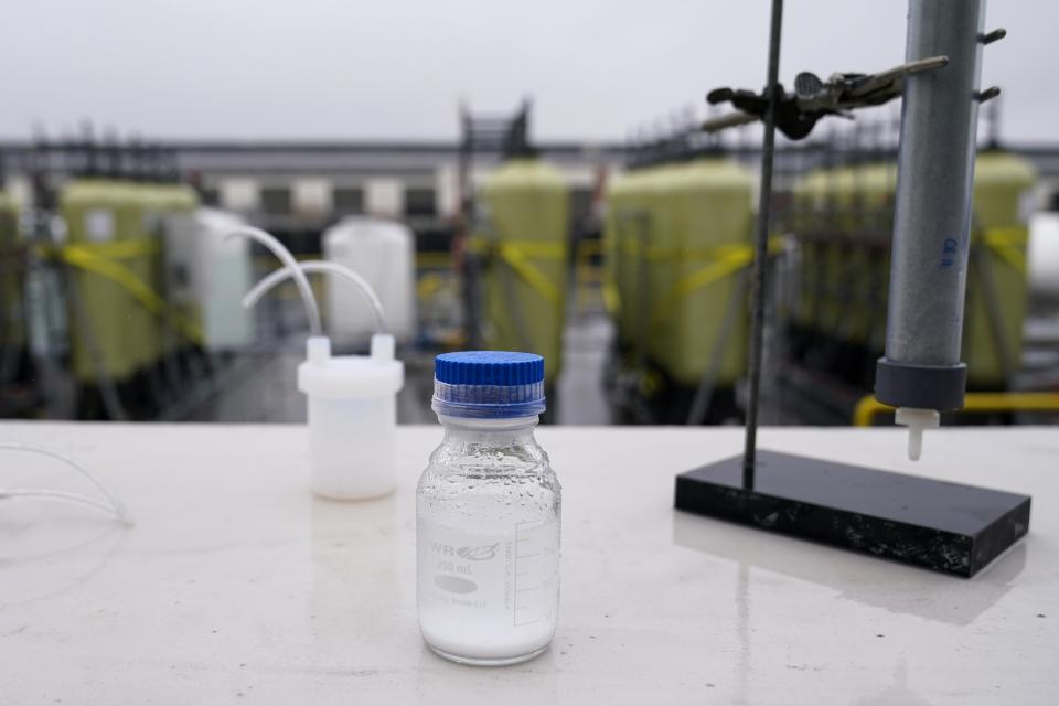 A container of calcium carbonate sits on a table near technology dubbed SeaChange, a seawater-based carbon removal pilot project, Wednesday, April 12, 2023, in San Pedro, Calif. The process sends an electrical charge through seawater flowing through a series of tanks on the barge. That then sets off a series of chemical reactions that bond the greenhouse gas to calcium carbonate, trapping it inside the mineral found in seashells. The seawater is then returned to the ocean to pull more carbon dioxide out of the air. (AP Photo/Ashley Landis)