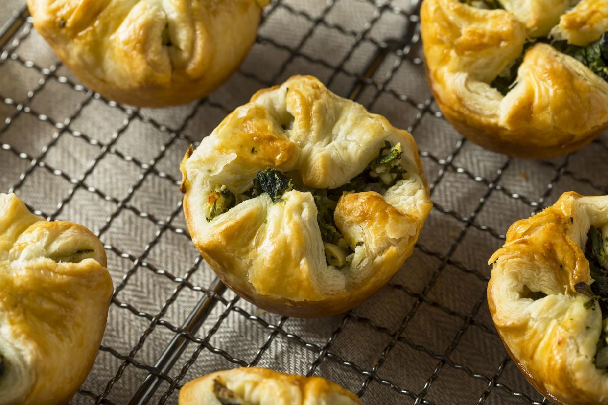 Closeup of mini spinach pies on a wire baking rack with a tan napkin underneath