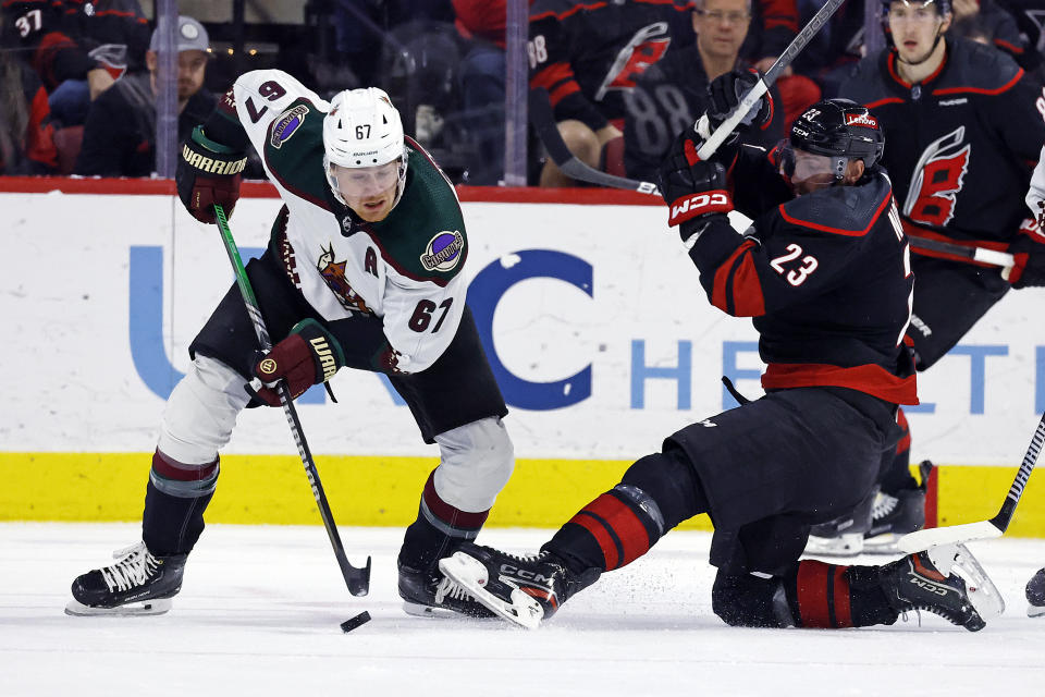 Arizona Coyotes' Lawson Crouse (67) takes the puck away from Carolina Hurricanes' Stefan Noesen (23) during the first period of an NHL hockey game Saturday, Jan. 27, 2024, in Raleigh, N.C. (AP Photo/Karl B DeBlaker)