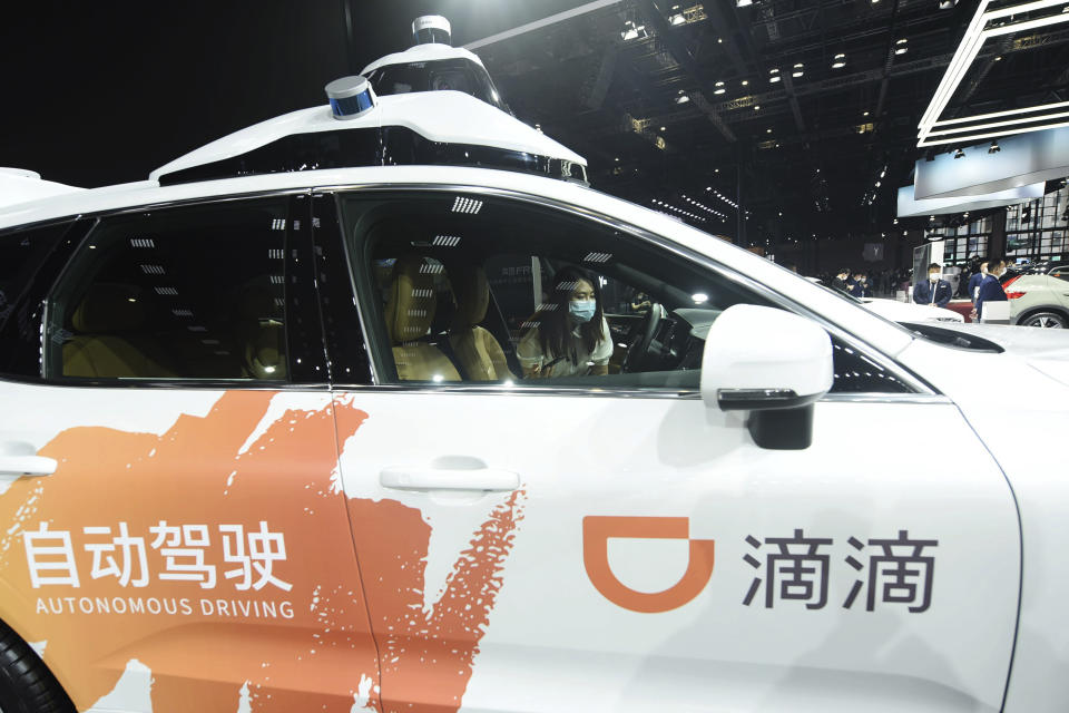 FILE - A visitor checks an autonomous car developed by Didi at an auto show in Shanghai, China on April 19, 2021. A grinding crackdown that wiped billions of dollars of value off Chinese technology companies is easing, but the once-freewheeling industry is bracing for much slower growth ahead. (Chinatopix via AP, File)