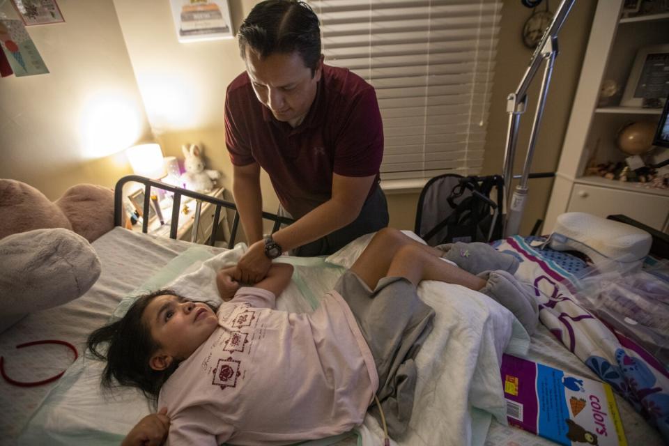 Gilbert Lopez tucks his daughter Hannah into bed at their Whittier home.