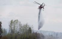 A helicopter drops water on a wildfire 16 kilometres south of Fort McMurray, Alta. on Highway 63, Sunday, May 8, 2016. THE CANADIAN PRESS/Jonathan Hayward