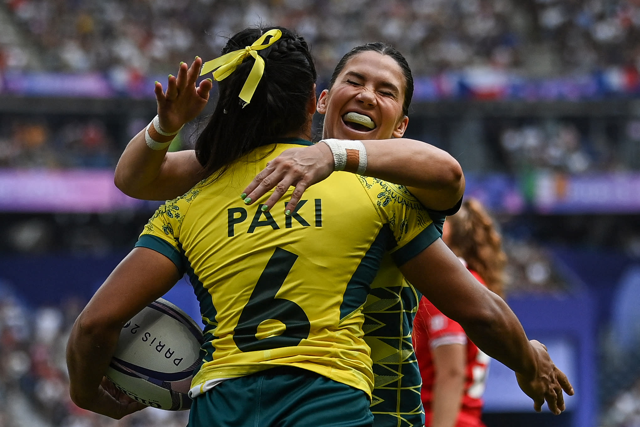 Australia's Sariah Paki (L) celebrates with teammates after scoring a try during the women's semi-final rugby sevens match between Canada and Australia during the Paris 2024 Olympic Games at the Stade de France in Saint-Denis on July 30, 2024. (Photo by CARL DE SOUZA / AFP)