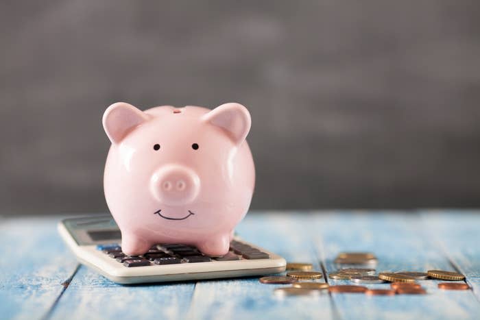 Piggy bank on a calculator with coins scattered around, symbolizing financial planning or savings