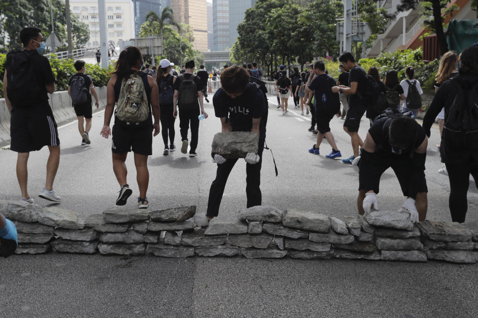 Protesters use stones to block a road in Hong Kong on Friday, June 21, 2019. Several hundred mainly student protesters gathered outside Hong Kong government offices Friday morning, with some blocking traffic on a major thoroughfare, after a deadline passed for meeting their demands related to controversial extradition legislation that many see as eroding the territory's judicial independence. (AP Photo/Kin Cheung)