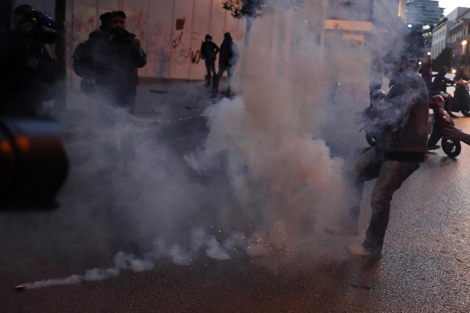 A protester kicks back a tear gas canister toward the riot police, during a protest near Parliament Square, In Beirut, Lebanon, Saturday, March. 13, 2021. Riot police fired tear gas to disperse scores of people who protested near parliament building in central Beirut Saturday amid deteriorating economic and financial conditions and as the local currency hit new low levels. (AP Photo/Bilal Hussein)