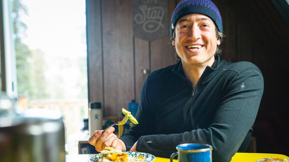 Men eating pasta in a hut wearing Smartwool clothing