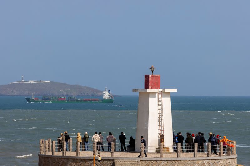 FILE PHOTO: People look across the strait from a lighthouse at the 68-nautical-mile scenic spot, on Pingtan Island