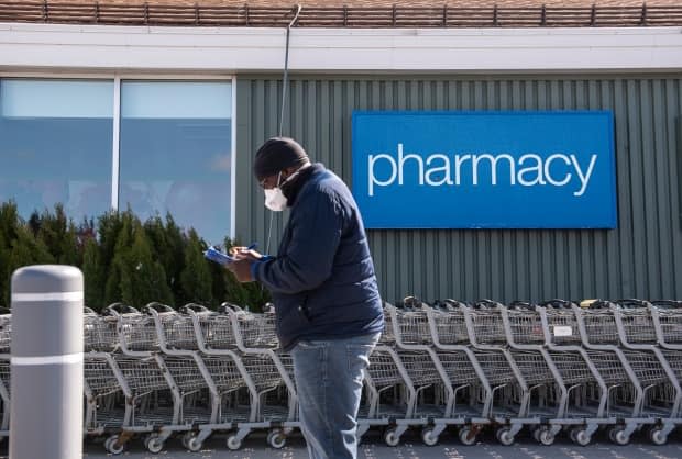 A person fills out paperwork as they line up for a COVID-19 vaccine at a Loblaws grocery store pharmacy in Ottawa April 26, 2021. (Justin Tang/Canadian Press - image credit)