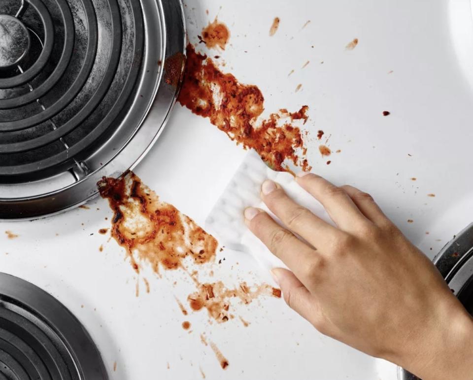 Model using a Mr. Clean Magic Eraser to clean up spilled sauce