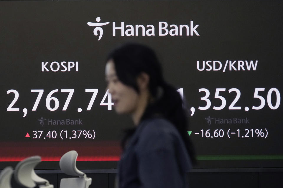 A currency trader passes by the screen showing the Korea Composite Stock Price Index (KOSPI), left, and the foreign exchange rate between U.S. dollar and South Korean won at the foreign exchange dealing room of the KEB Hana Bank headquarters in Seoul, South Korea, Thursday, May 16, 2024. (AP Photo/Ahn Young-joon)