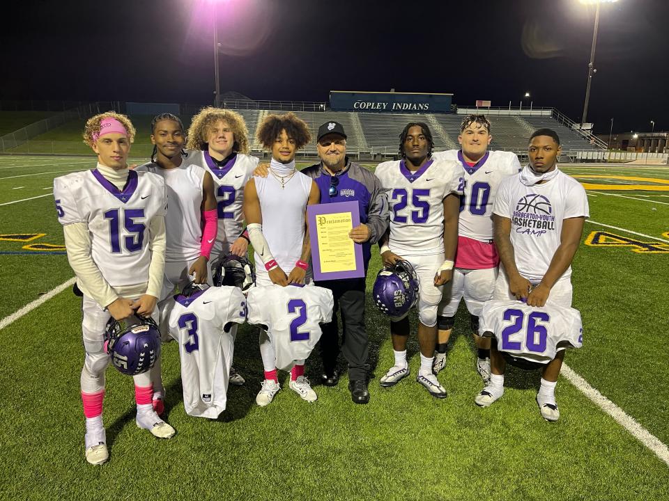 Tony Gotto, standing with a proclamation in his hands, smiles Friday after a win over Copley that made him Barberton's winningest football coach. Players, from left, are Noah DeHart, Angelo Harper, Dominic Wilson, Kenny Larry, Josiah Wright, Brayden Stefan and Xzavier Macon.