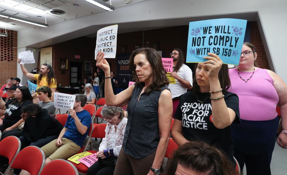 Noelle Tennis Gulden, right, and Carla Wallace, of SURJ, held signs opposing the implementation of SB 150 during a meeting of the Jefferson County Board of Education at the Vanhoose Education Center in Louisville, Ky. on Aug. 7, 2023.  