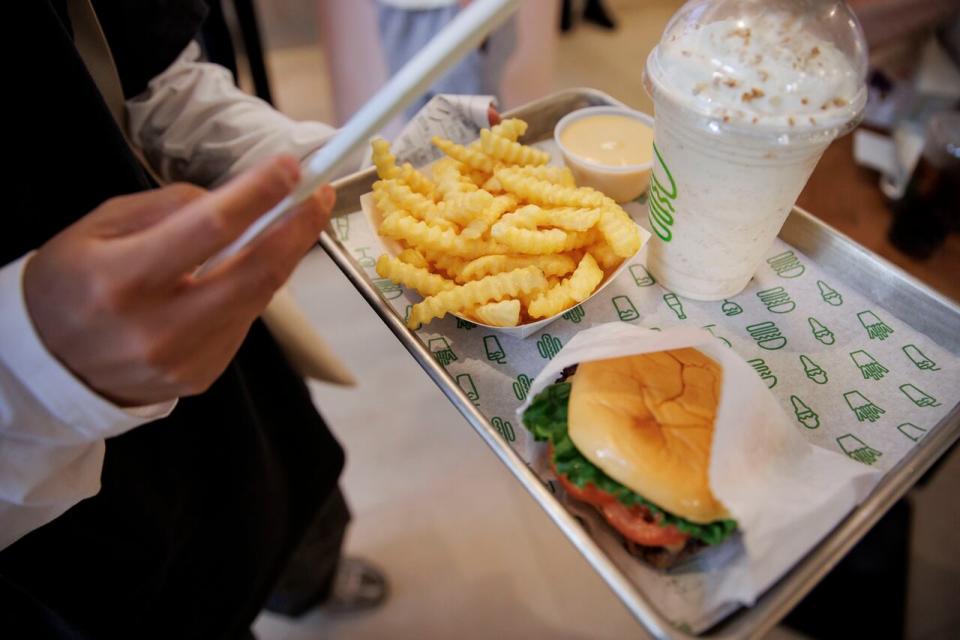 A customer holds a tray with a burger, fries and milkshake at Shake Shack on Thursday.