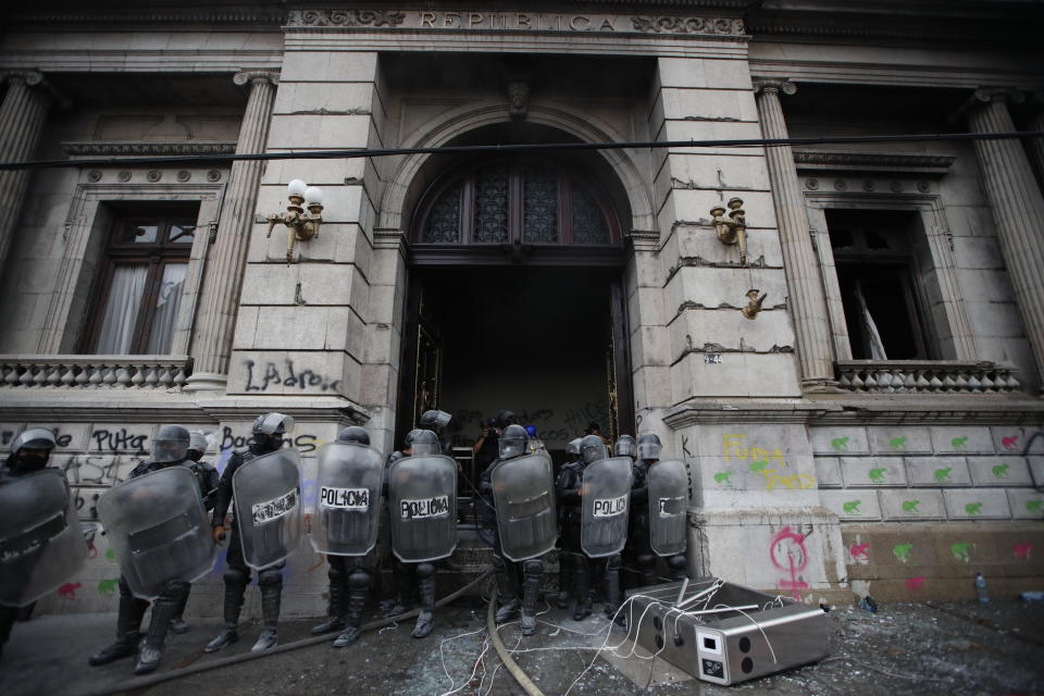 Police surround the Congress building after protesters set a part of it on fire, in Guatemala City, Saturday, Nov. 21, 2020. Hundreds of protesters were protesting in various parts of the country Saturday against Guatemalan President Alejandro Giammattei and members of Congress for the approval of the 2021 budget that reduced funds for education, health and the fight for human rights. (AP Photo/Moises Castillo)