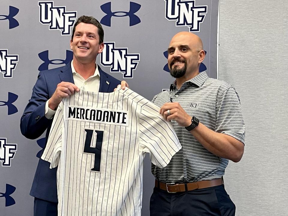 University of North Florida athletic director Nick Morrow (left) presents new baseball coach Joe Mercadante with his jersey during a news conference at the UNF Arena on Thursday.