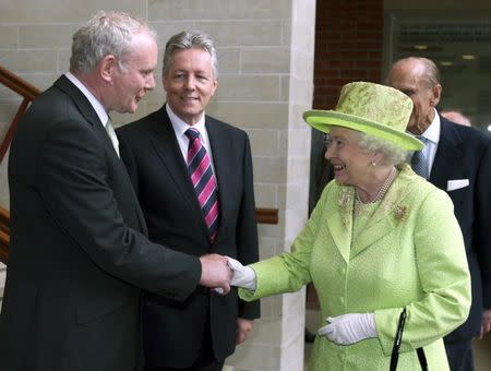 Britain's Queen Elizabeth shakes hands with Northern Ireland deputy first minister Martin McGuinness, watched by first minister Peter Robinson (C) at the Lyric Theatre in Belfast June 27, 2012. REUTERS/Paul Faith/pool/Files