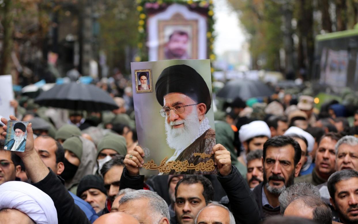 A man holds a photo of Iranian Supreme Leader Ayatollah Ali Khamanei as people attend a funeral ceremony of two security officers, who lost their lives in petrol price hike protests, in Tehran, Iran - Anadolu