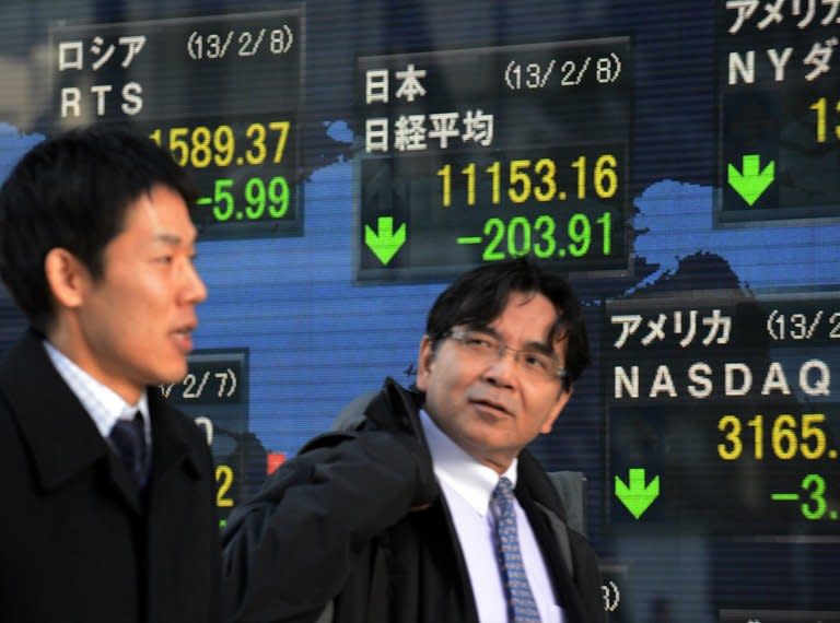 Businessmen pass before a share prices board in Tokyo. Asian stocks were mixed while the euro eased on Friday as data showed the eurozone slipped deeper into recession at the end of last year, while markets await the start of a Group of 20 meeting in Russia