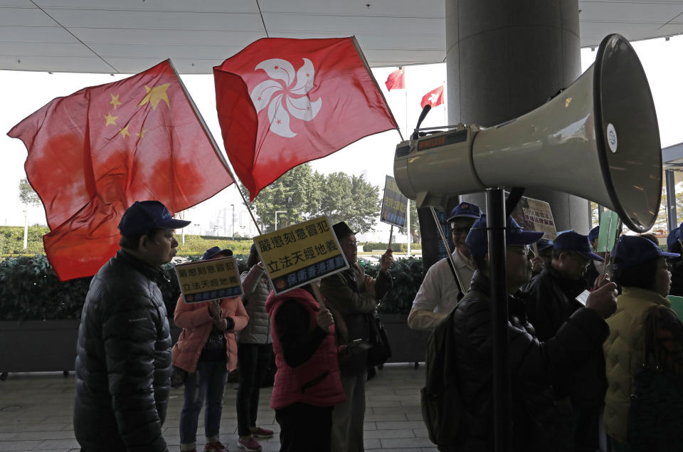 Pro-Beijing demonstrators raise the Chinese National flag and the Hong Kong flag during a protest outside Legislative building in Hong Kong, Wednesday, Jan. 23, 2019. Hong Kong’s legislature has taken up for consideration a bill that punishes anyone who "publicly and intentionally insults" the Chinese national anthem with up to three years in prison. (AP Photo/Vincent Yu)