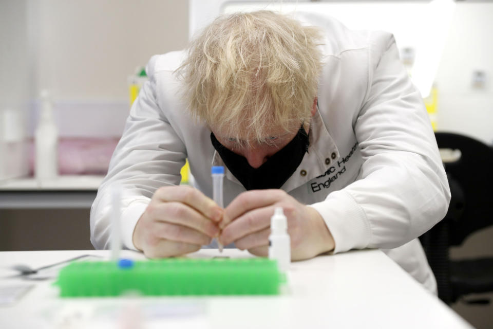 Britain's Prime Minister Boris Johnson, wearing a mask because of the coronavirus, has a close look at a sample at the Lateral Flow Testing Laboratory during a visit to the Public Health England site at Porton Down science park near Salisbury, southern England, on Friday Nov. 27, 2020. (Adrian Dennis/Pool via AP)