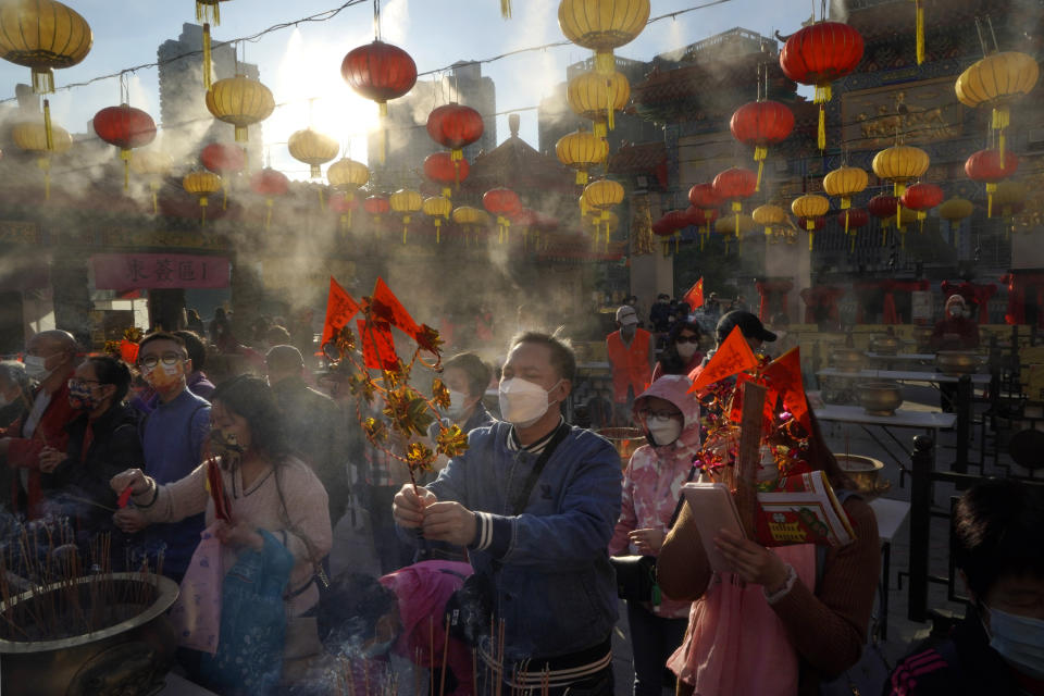 Worshippers wearing face masks to protect against the spread of the coronavirus burn joss sticks as they pray at the Wong Tai Sin Temple, in Hong Kong, Friday, Feb. 12, 2021, to celebrate the Lunar New Year which marks the Year of the Ox in the Chinese zodiac. (AP Photo/Kin Cheung)