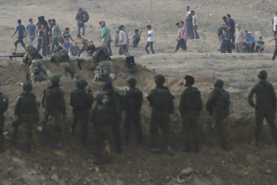 Israeli soldiers stand guard as Palestinian protesters arrive during a protest along the Israel Gaza border, Israel , Friday, Oct. 19, 2018. (AP Photo/Ariel Schalit)