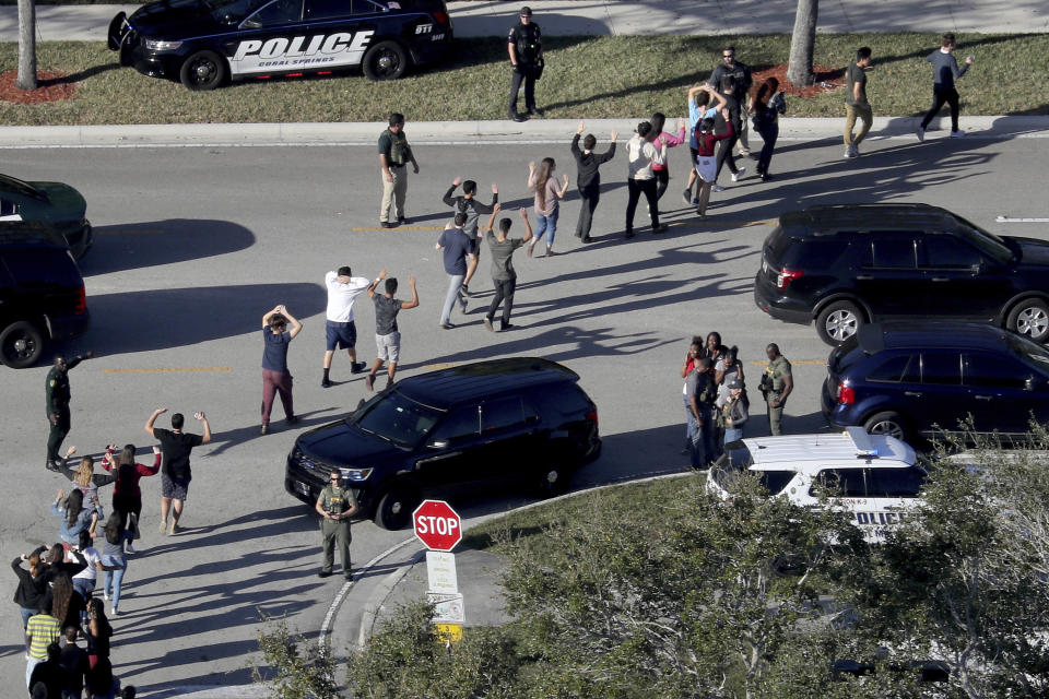 FILE - In this Feb. 14, 2018 file photo, students hold their hands in the air as they are evacuated by police from Marjory Stoneman Douglas High School in Parkland, Fla., after a shooter opened fire on the campus. Sorrow is reverberating across the country Sunday, Feb. 14, 2021, as Americans joined a Florida community in remembering the 17 lives lost three years ago in the Parkland school shooting massacre. President Joe Biden used the the occasion to call on Congress to strengthen gun laws, including requiring background checks on all gun sales and banning assault weapons (Mike Stocker/South Florida Sun-Sentinel via AP, File)