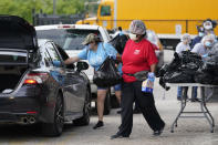 In this Monday, April 6, 2020, photo, Vicky Dickson, with Houston Independent School District Nutrition Services, helps distribute food in Houston, amid the coronavirus pandemic. HISD relaunched their food distribution efforts throughout the district, with a streamlined process that will implement increased safety measures. (AP Photo/David J. Phillip)