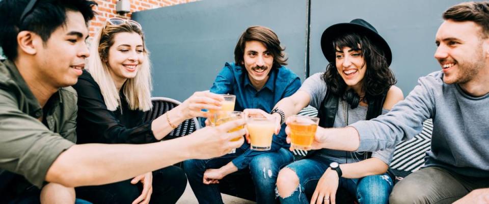 Group of young multiethnic friends sitting in a bar toasting, talking to each other, having fun - happy hour, friendship, relax concept