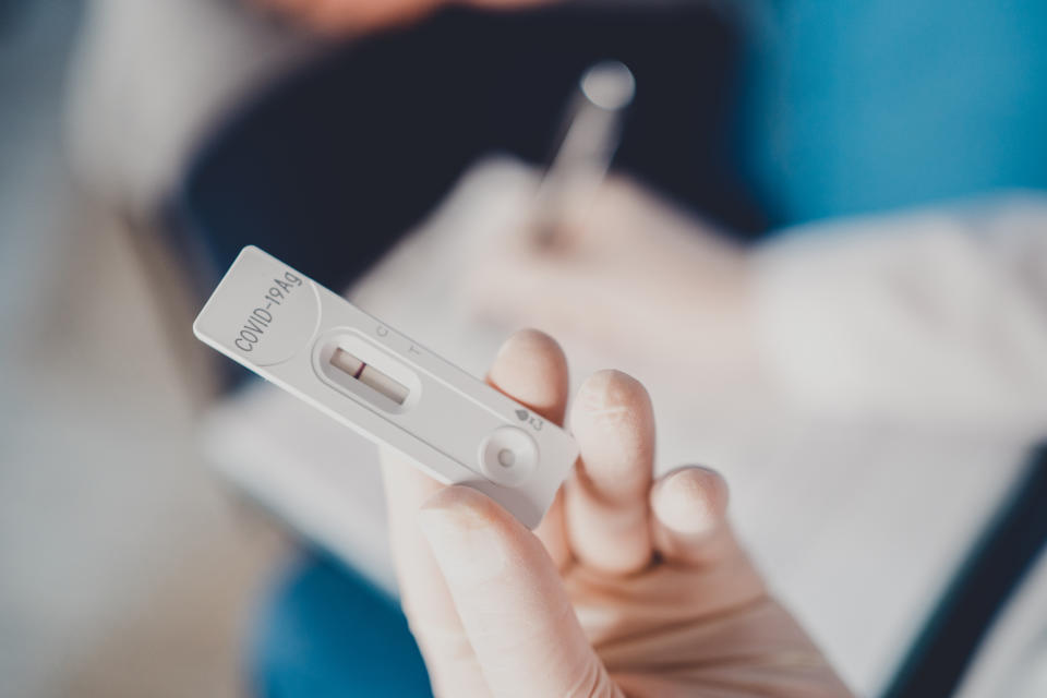 Close-up shot of doctor's hand with protective gloves holding a negative test device to senior patient. Doctor hand holding negative Coronavirus/Covid-19 rapid test.