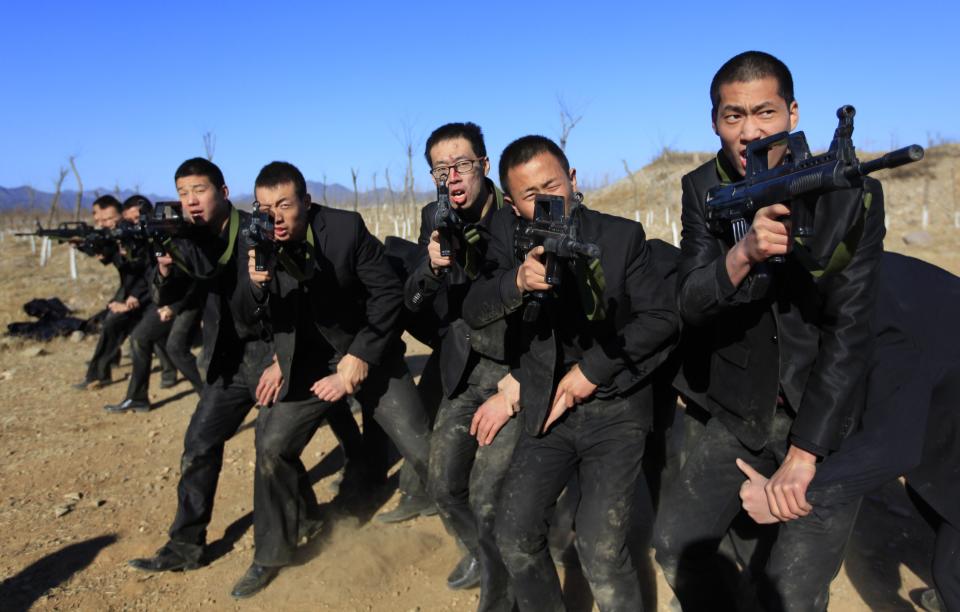 Students holding replica 95 semi-automatic rifles practice protecting their employers at a shooting training field managed by the military during the Tianjiao Special Guard/Security Consultant training on the outskirts of Beijing