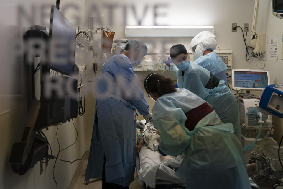 FILE - In this Nov. 19, 2020, file photo, EMT Giselle Dorgalli, second from right, looks at a monitor while performing chest compression on a patient who tested positive for coronavirus in the emergency room at Providence Holy Cross Medical Center in the Mission Hills section of Los Angeles. California’s hospitals are being overwhelmed by a surge of coronavirus patients and some say the worst is yet to come. (AP Photo/Jae C. Hong, File)