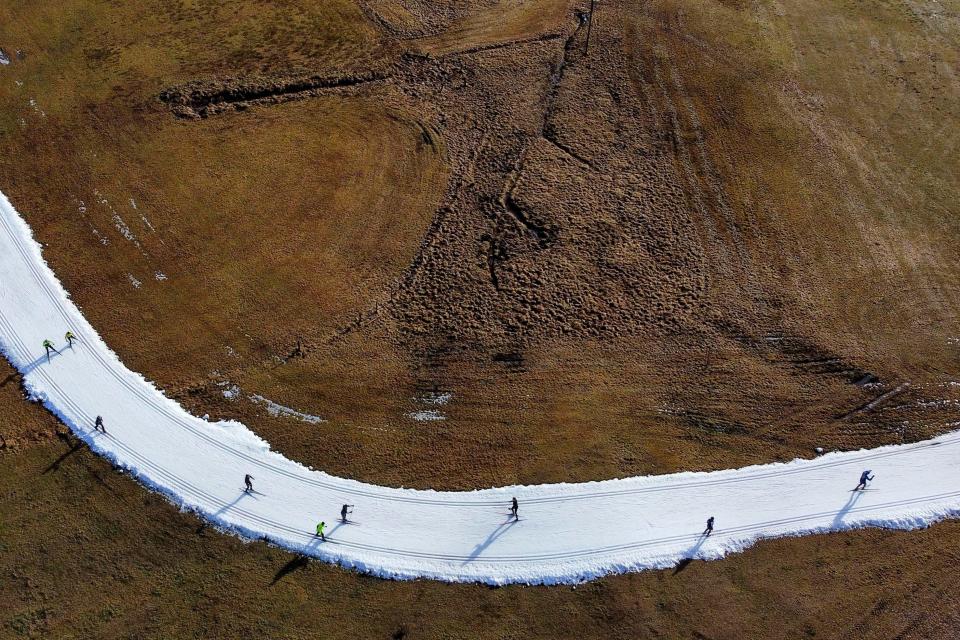 People skiing on a cross country slope in Ramsau, Austria, Friday, Jan. 6, 2023. Sparse snowfall and unseasonably warm weather in much of Europe is allowing green grass to blanket many mountaintops across the region where snow might normally be. It has caused headaches for ski slope operators and aficionados of Alpine white this time of year.