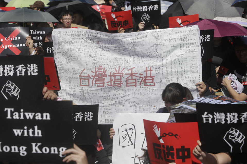 Supporters hold a placard with signatures and a slogan reading "Taiwan Supports Hong Kong" to oppose Hong Kong's extradition law outside the Legislative Yuan in Taipei, Taiwan, Sunday, June 16, 2019. Hong Kong residents Sunday continued their massive protest over an unpopular extradition bill that has highlighted the territory's apprehension about relations with mainland China, a week after the crisis brought as many as 1 million into the streets. (AP Photo/Chiang Ying-ying)