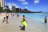 Beach goers take to the waves on Waikiki Beach, Thursday, June, 23, 2022 in Honolulu. In a major expansion of gun rights after a series of mass shootings, the Supreme Court said Thursday that Americans have a right to carry firearms in public for self-defense.