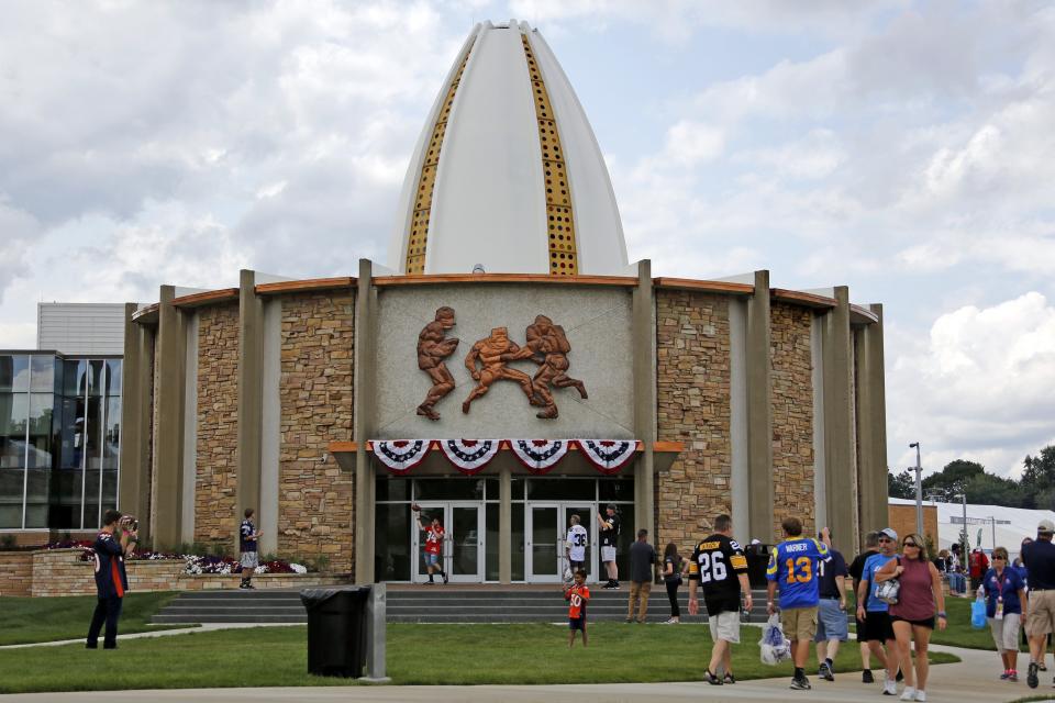 FILE - In this Aug. 5, 2017, file photo, football fans toss footballs on the lawn outside the Pro Football Hall of Fame in Canton, Ohio. (AP Photo/Gene J. Puskar, File)
