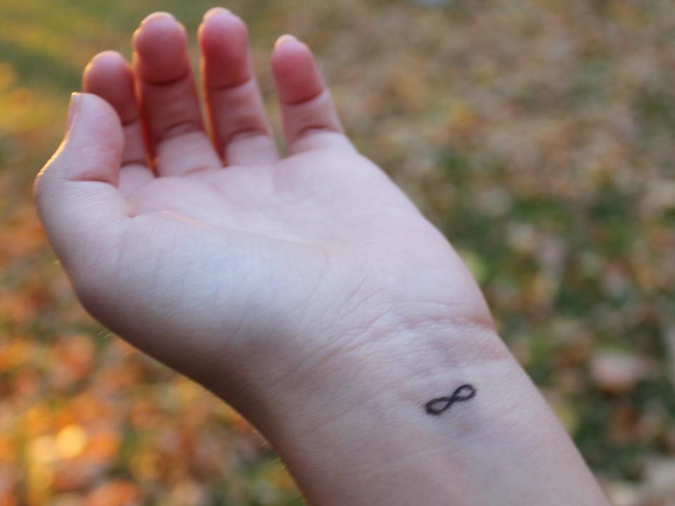 Small infinity symbol tattoo on the inside of someone's wrist.