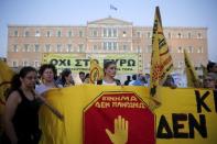 Anti-austerity protesters hold a banner during a rally in front of the parliament building in Athens, July 22, 2015. REUTERS/Alkis Konstantinidis