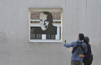 A couple takes a photo of a portrait of Colombian Nobel laureate Gabriel Garcia Marquez in front of the Casa de la Moneda Museum in downtown Bogota, Colombia, Thursday, April 17, 2014. Garcia Marquez died in Mexico City on Thursday. The author was among Latin America's most popular writers and widely considered the father of a literary style known as magic realism. (AP Photo/Diana Sanchez)