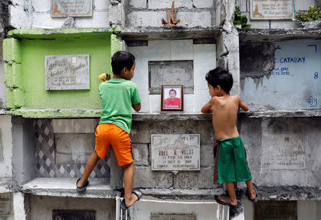 Boys look at the tomb of Michael Almeda, who was among those allegedly killed by the Bonnet Gang, in more than 60 drug-related vigilante killings in the town of Pateros, Metro Manila, Philippines March 15, 2017. Picture taken March 15, 2017. REUTERS/Erik De Castro TPX IMAGES OF THE DAY