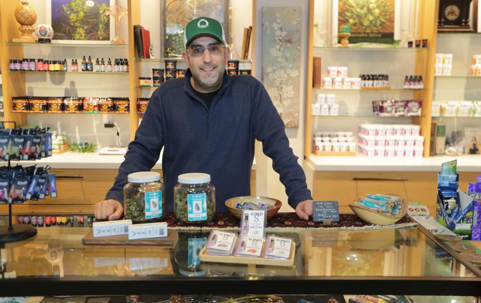 Kind Oasis CBD co-owner Salem Kashou stands before an assortment of Delta-8 products at Kind Oasis CBD on North Farwell Avenue in Milwaukee  on Thursday, Dec. 16, 2021. Kind Oasis sells Delta-8 products, a Hemp-derived product that is sold around Wisconsin that produces a similar “high” that cannabis produces while still being legal.