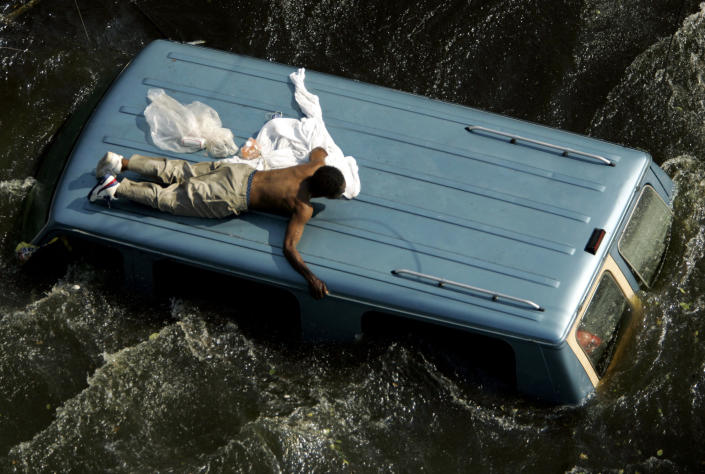 A man clings to the top of a vehicle before being rescued by the U.S. Coast Guard from the flooded streets of New Orleans in the aftermath of Hurricane Katrina, September 4, 2005. REUTERS/Robert Galbraith