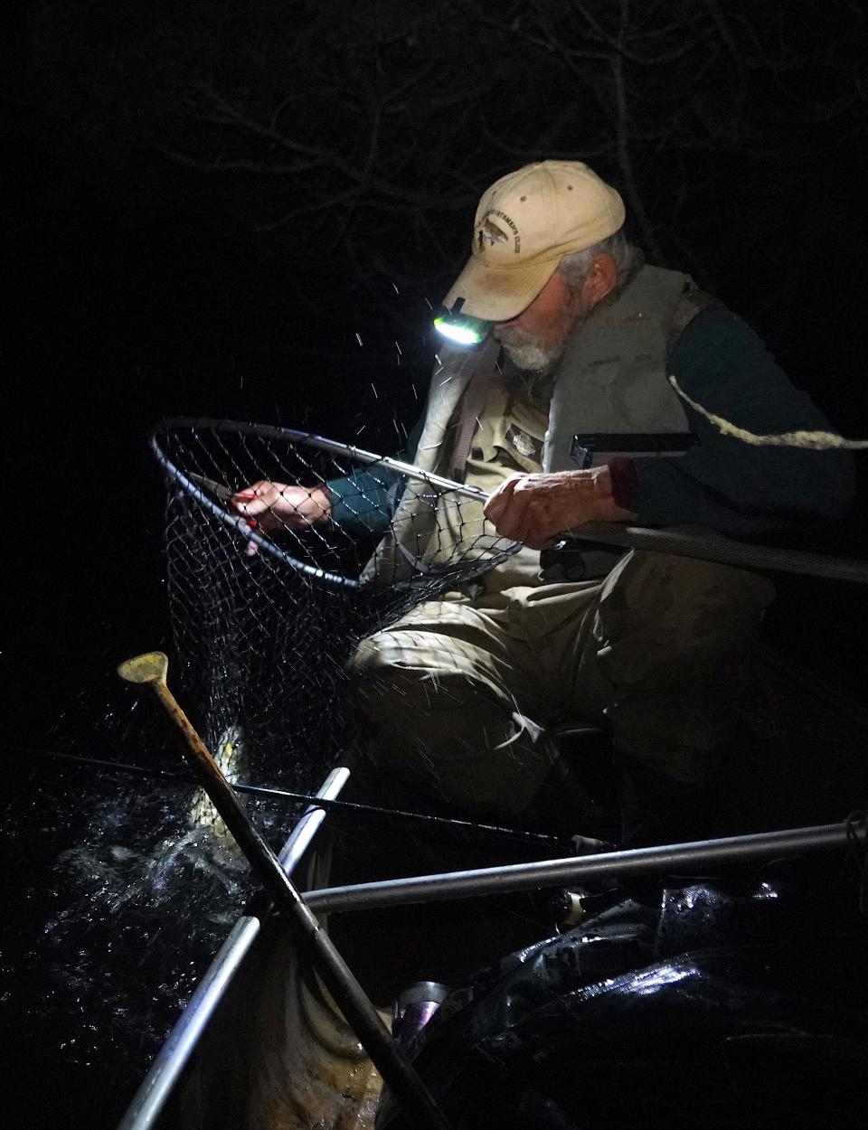 Ken Lundberg of Lake Nebagamon nets a brown trout while fishing at night on the Bois Brule River.