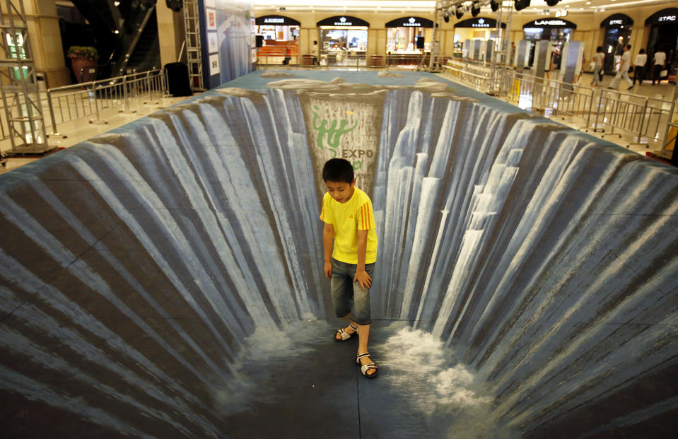 A young visitor stands on a three dimensional visual effect painting at a shopping mall Friday Aug. 14, 2009 in Shanghai, China. The 3D painting with the theme of the Shanghai World Expo is made by Edgar Mueller. (AP Photo/Eugene Hoshiko)